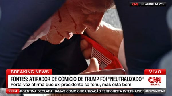 Trump agaixado com sangue no rosto após tiros em comício (Foto: CNN/Reprodução)
